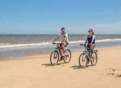 A couple riding their bicycles on the beach